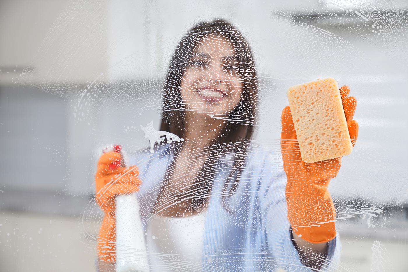 Cleaner in rubber gloves washing a window
